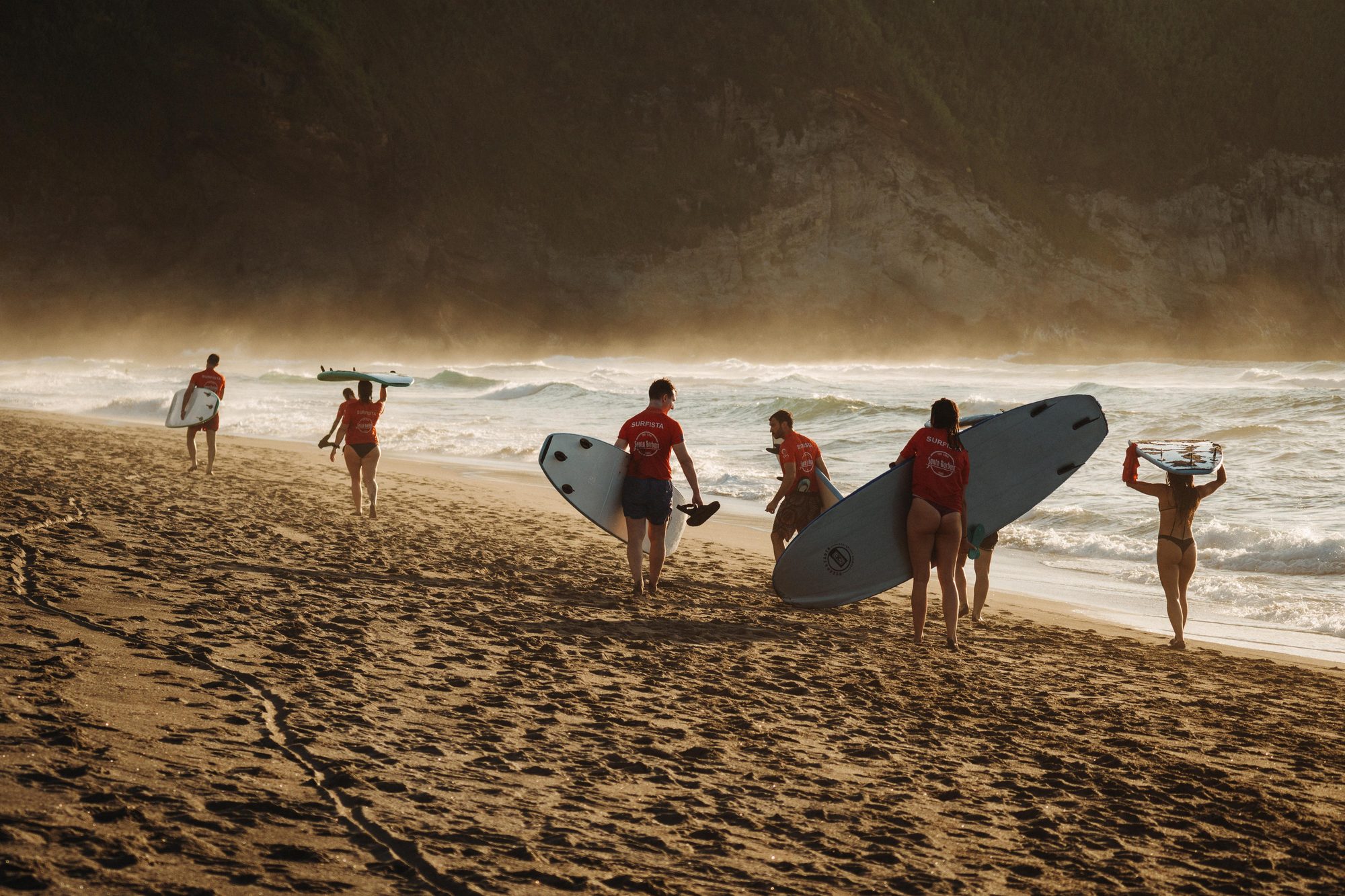 Surfers heading out at golden hour in São Miguel